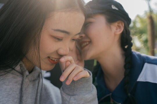 two young Asian female friends whisper
