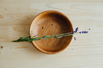 A plate of natural wood with sprigs of lavender.