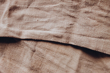 Linen table cloth texture with deep shadows in brown color. Coutry cozy home fabric atmosphere. Top view. Copy space on background