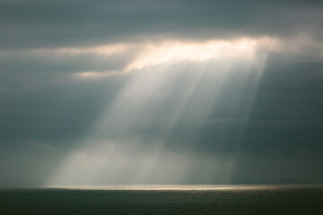 Sunlight streaming through a cloudy sky onto the ocean