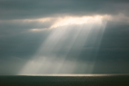 Sunlight streaming through a cloudy sky onto the ocean