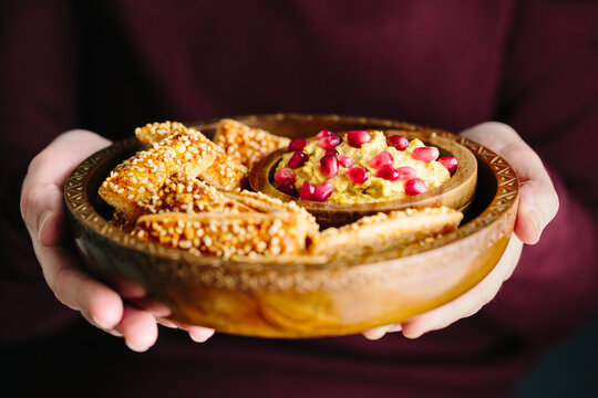 Woman holding dish of Cheese Bites with houmous dip and pomegran