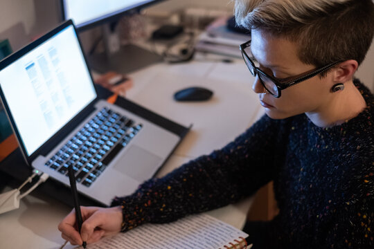 Close Up Of Female Student Writing On Notebook In Front Of The Computer