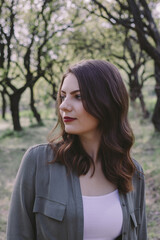 Obraz premium Portrait of a beautiful brunette young woman in the tree garden. Outdoors, spring time.