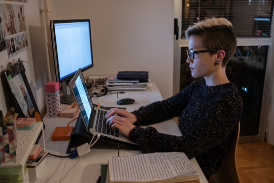 Young Short-Haired Woman With Glasses Using Laptop Late At Night