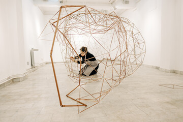 Female Artist Assembling Metal Sculpture In The Art Gallery