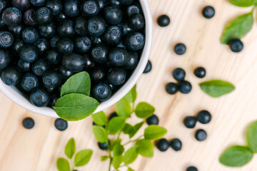 Fresh bilberries in a cup on the wooden table. Macro shot. Top view.