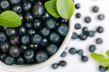 Fresh bilberries in a cup on the white table. Macro shot. Top view.
