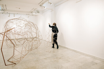 Female Sculptor Carrying A Piece Of A Complex Metal Sculpture