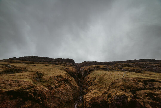 Narrow ravine on rocky terrain in overcast weather