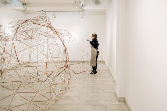 Female Artist Assembling An Abstract Metal Sculpture In The Art Gallery