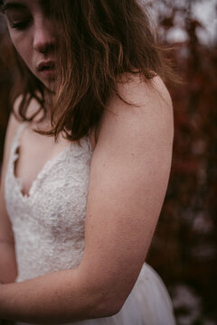 Crop sensual bride in dress standing in cold woods