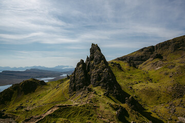 Rocky formations against misty river shoreline and mountain crests at horizon in sunny day