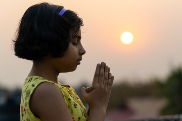Girl offering prayer at sunrise