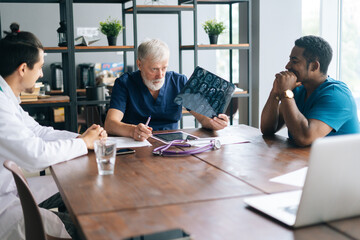 Fototapeta premium Team of multi-ethnic medical specialists discussing at X-ray image of together during medical conference. Concept of medicine and health care.