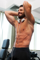 Young man with headphones in gym, working out, listening to music