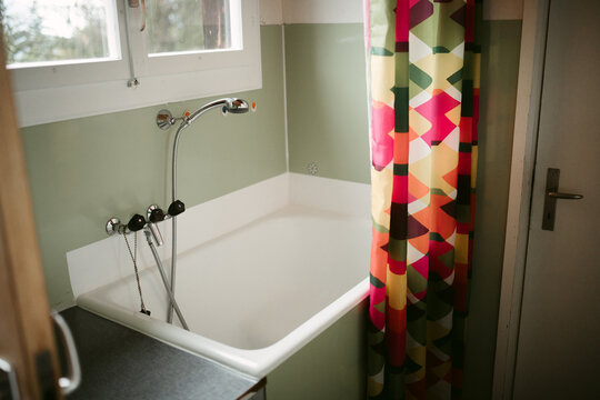 Bathtub with shower faucet and colorful curtain