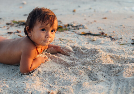 Baby playing with send on beach