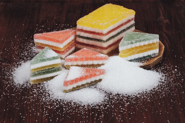 Fototapeta na wymiar Multi-colored marmalade jelly candy's. Heap of triangular and rectangular marmalade candy covered with sugar on wooden background.