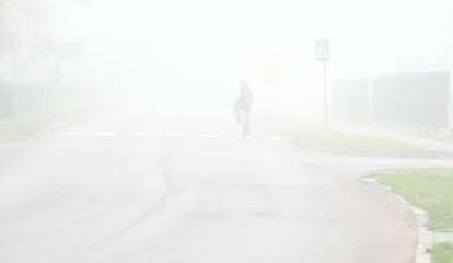 Rowerzysta we mgle jedzie ulicą