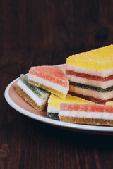Colorful jelly candy in the plate on wooden background. Multi-colored marmalade jelly candy's. Heap of triangular and rectangular  marmalade candy.