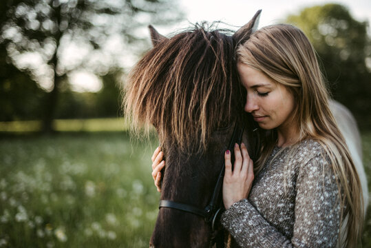 Tranquil woman hugging horse in nature