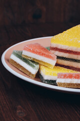 Colorful jelly candy in the plate on wooden background. Multi-colored marmalade jelly candy's. Heap of triangular and rectangular  marmalade candy.