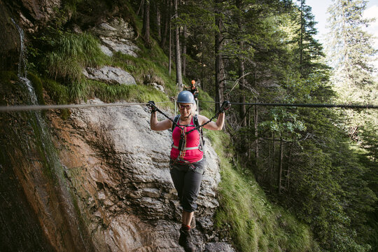 Brave female climber walking on stretched rope in mountains