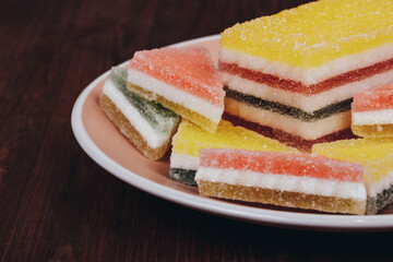 Colorful jelly candy in the plate on wooden background. Multi-colored marmalade jelly candy's. Heap of triangular and rectangular  marmalade candy.
