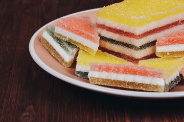 Colorful jelly candy in the plate on wooden background. Multi-colored marmalade jelly candy's. Heap of triangular and rectangular  marmalade candy.
