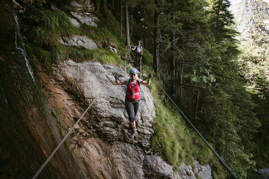 Female climber walking tightrope near bumpy cliff in afternoon