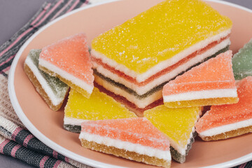 Colorful jelly candy in the plate at checkered napkin on grey background. Multi-colored marmalade jelly candy's. Heap of triangular and rectangular  marmalade candy.