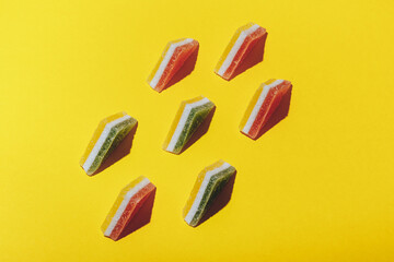 Set of colorful triangular jelly candy lined up on yellow background. Multi-colored marmalade jelly candy's. Top view.