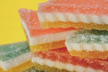 Multi-colored marmalade jelly candy's. Heap of triangular marmalade candy on yellow background. Macro, selective focus.