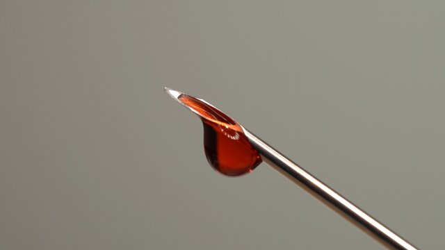 Drops of blood from the tip of the medical syringe. Bloody liquid dripping from needle, macro close up. Addiction horror illustration. Used syringe needle in blood. Administration of street drugs. - Powered by Adobe