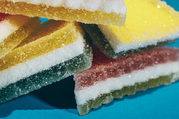 Multi-colored marmalade jelly candy's. Heap of triangular marmalade candy on blue background. Macro, selective focus.