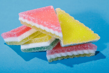 Heap of triangular marmalade candy on blue background. Multi-colored marmalade jelly candy's. 