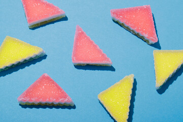 Randomly located colorful triangular jelly candy on blue background. Multi-colored marmalade jelly candy's. Scattered marmalade. Top view.