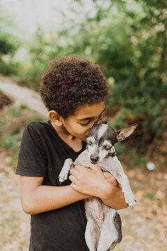 Mixed race boy hugging a little chihuahua bitch in the garden