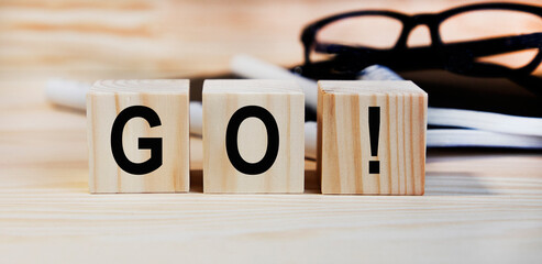 On wooden cubes the text go, in the background glasses.