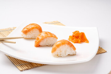 Rice and salmon nigiri on white plate and white background.