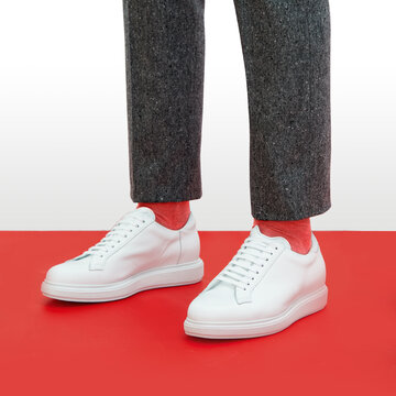 A man in white sneakers stands on a red background.