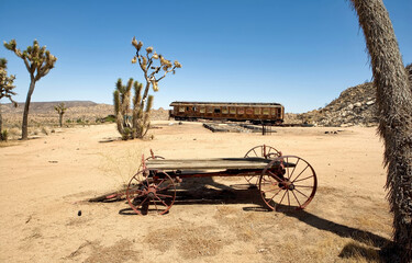 Burned out railroad car and old wagon in the desert