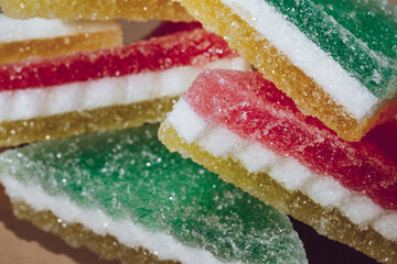 Multi-colored marmalade jelly candy's. Heap of triangular marmalade candy on beige background. Macro, selective focus.