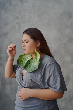 portrait of an Asian woman in a dress cabbage earrings on a gray background