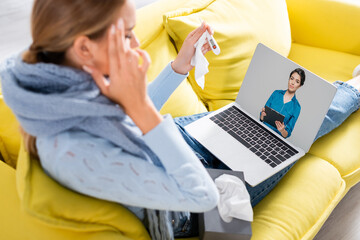 Woman with clipboard on screen of laptop near ill freelancer holding thermometer and napkin during...
