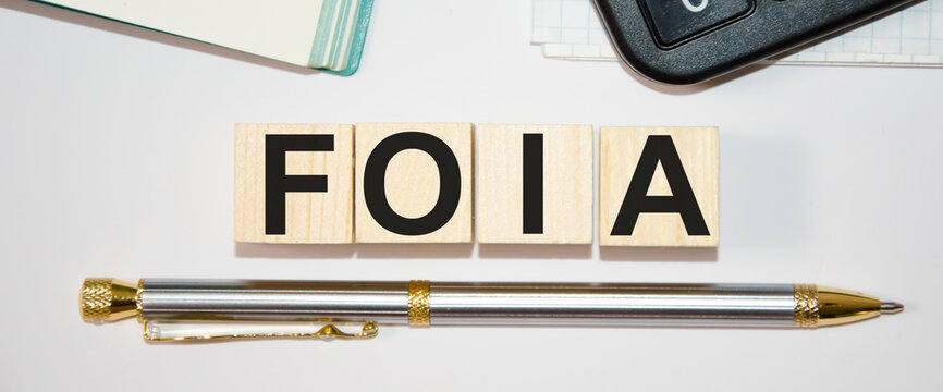 Focused on the business concept. The word foia is written on cubes with a calculator and a pen. Business concept. Search idea. law. girl holding an inscription