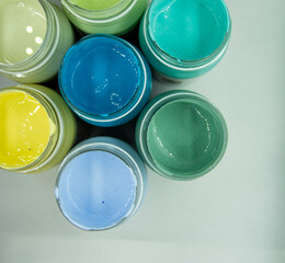Jars of acrylic paint in green, blue, yellow shades close-up.