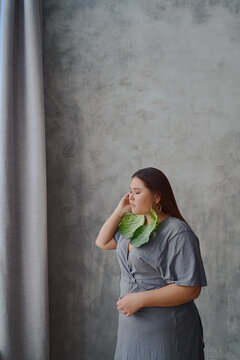 portrait of an Asian woman in a dress cabbage earrings on a gray background