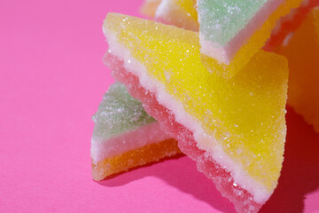 Heap of triangular jelly candy on pink background. Macro, selective focus.